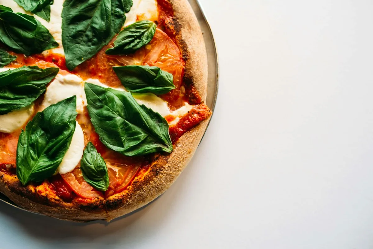 Finished Margherita pizza with tomato, melted mozzarella, and fresh basil